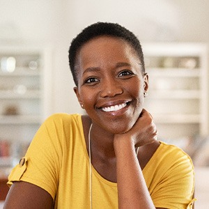 Woman in yellow shirt smiling at home